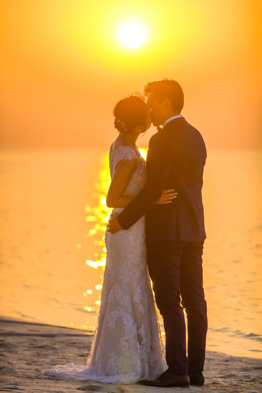 man and woman kissing under sunset