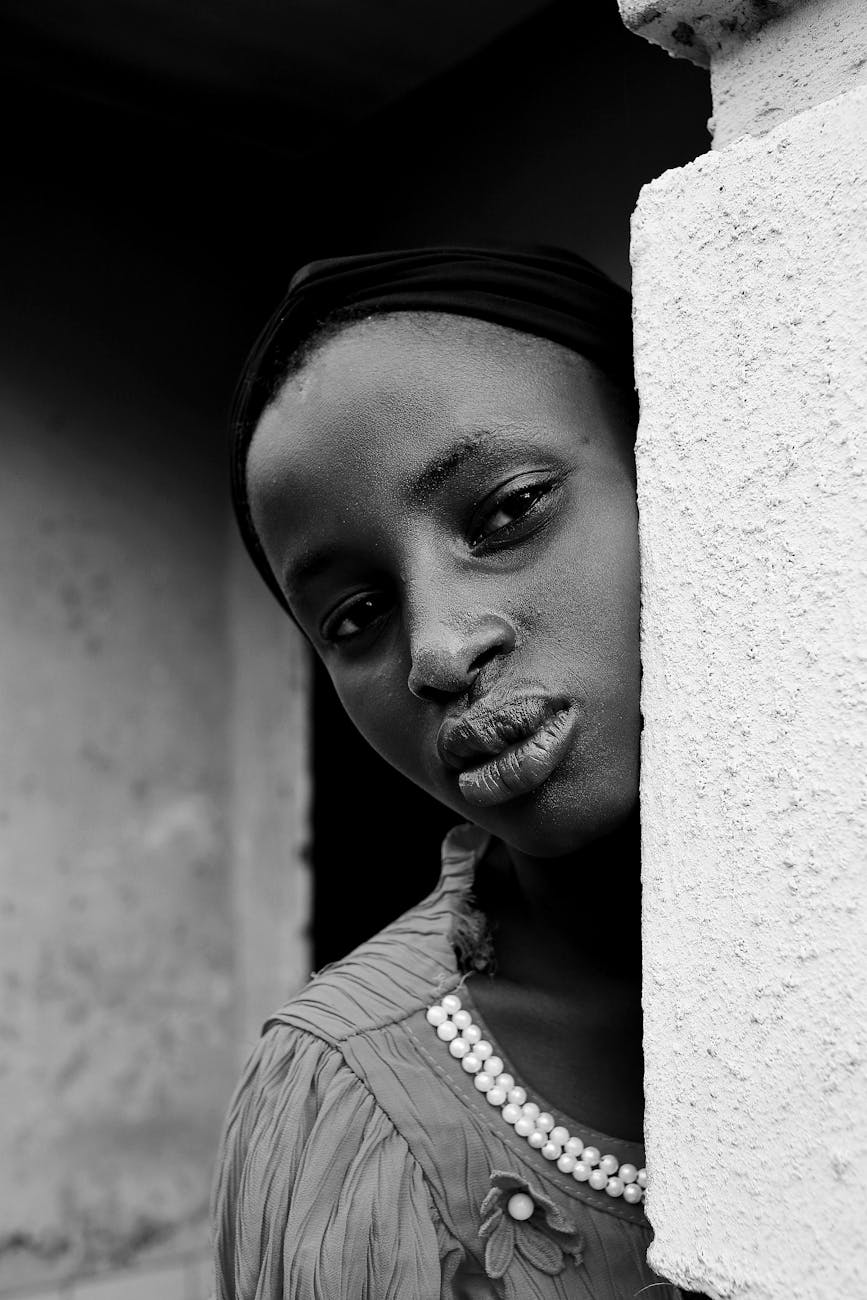 young woman looking from behind the corner of a building